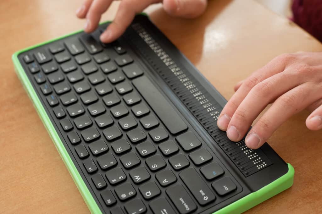 Zugänglichkeit 6 Ein blinder Mann benutzt einen Computer mit einer Braillezeile und einer Computertastatur. Inklusives Gerät