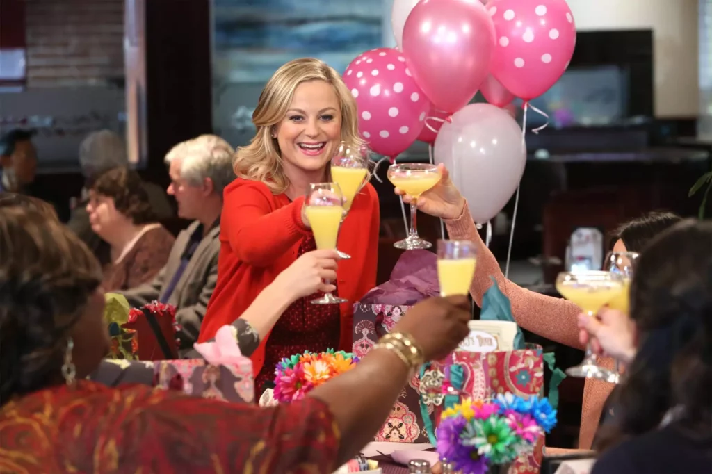 So You Don’t Sell Flowers or Candy, Can Valentine’s Day 2025 Still Be Profitable For You? 3 An image of a blonde woman lifting a champagne glass surrounded by pink balloons and other woman holding champagne glasses